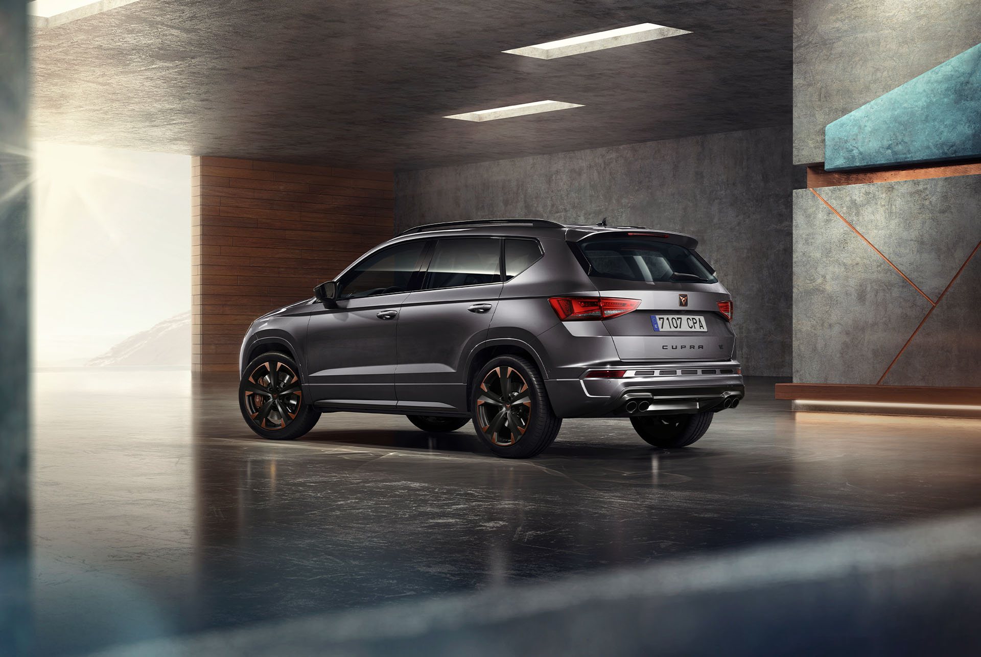 Pelēks CUPRA Ateca SUV uz balta fona. Automobilim ir izteiksmīgs priekšējais režģis, LED priekšējie lukturi un vieglmetāla diski ar vara akcentiem, kas izceļ tā sportisko dizainu.